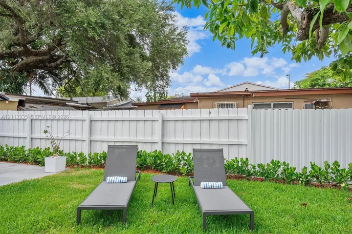 Backyard featuring a manicured lawn, privacy fencing, and mature canopy trees