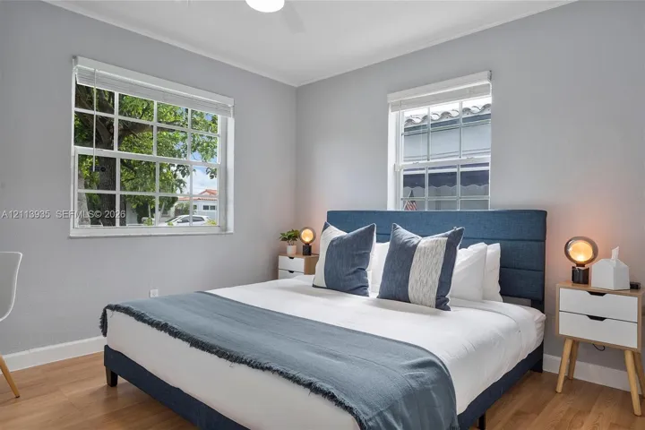 Room featuring wood-finish flooring, dual windows with muntins, neutral wall tones, and a ceiling fan