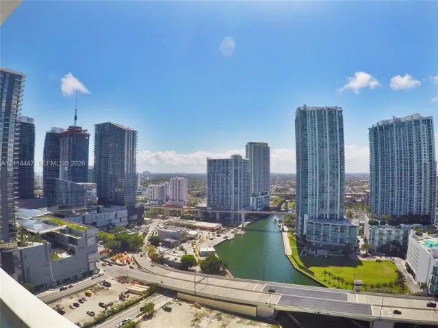 High-rise perspective featuring expansive glass-clad skyscrapers, a canal, and elevated transportation infrastructure