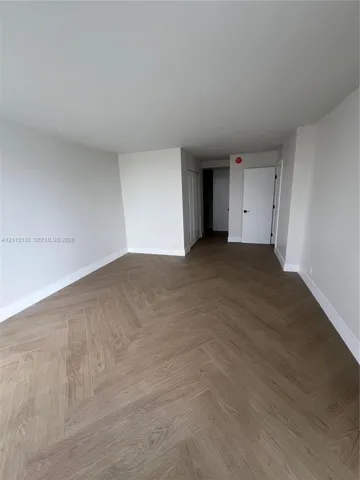 Neutral-toned interior space featuring herringbone-pattern wood-finish flooring and solid core swing doors