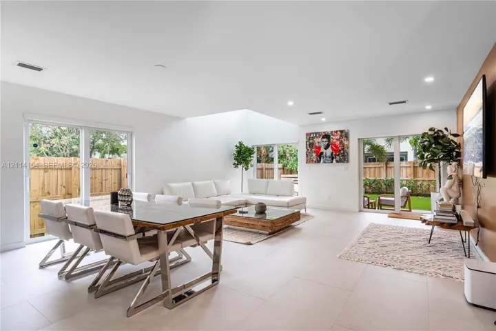 Open-concept room featuring light-toned tile flooring, recessed ceiling lighting, a large skylight, and dual sliding glass doors