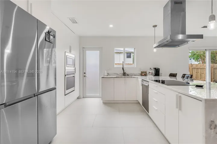 Modern kitchen featuring flat-panel cabinetry, stone countertops, stainless steel appliances, a chimney-style range hood, and large-format tile flooring