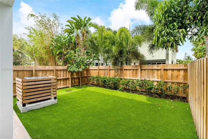 Private backyard featuring synthetic turf, vertical wood privacy fencing, and a built-in wood slat HVAC enclosure