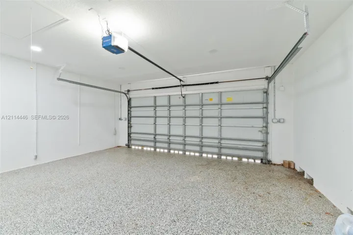 Two-car garage featuring epoxy-coated flooring, white interior walls, and an automated overhead door system