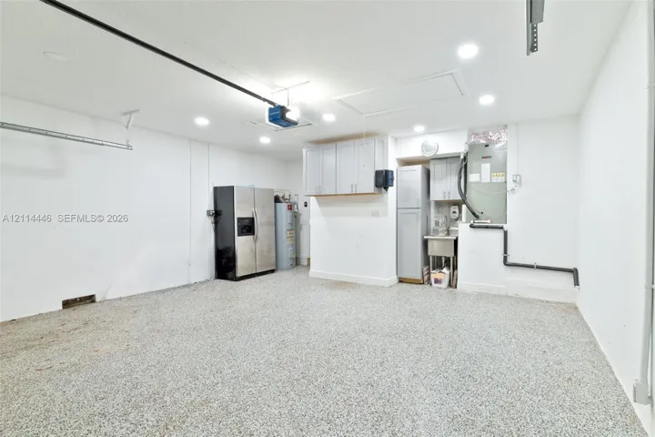 Garage space featuring an epoxy-coated floor, recessed lighting, built-in storage cabinetry, and a dedicated utility sink area