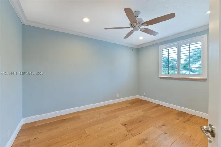 Interior room featuring wood-finish flooring, recessed lighting, crown molding, a ceiling fan, and a window fitted with plantation shutters