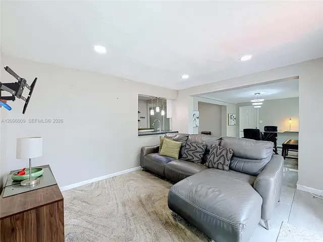 Living area featuring neutral-toned walls, recessed lighting, and a pass-through window to the kitchen