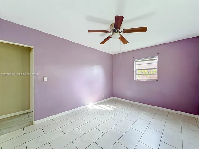 Room featuring light-colored tile flooring, a multi-blade ceiling fan, and a window with horizontal blinds