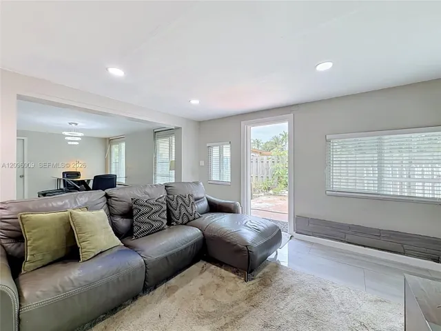 Light-filled interior featuring smooth-finish ceilings with recessed lighting, tile flooring, large windows with horizontal blinds, and a door providing exterior access