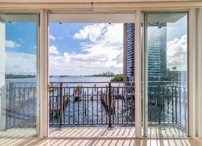 Triple-panel sliding glass doors opening to a balcony with metal railings and water frontage