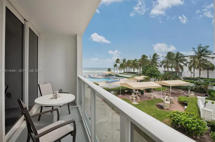 Covered balcony featuring a glass-panel railing, concrete flooring, and a sliding glass door entry