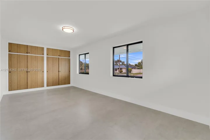 Neutral wall tones, wood-finish built-in cabinetry, large-format tile flooring, and windows with black frames