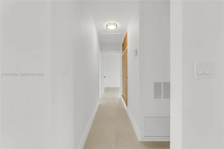 Neutral color palette, tile flooring, flush-mount circular lighting fixture, and floor-to-ceiling wooden cabinetry
