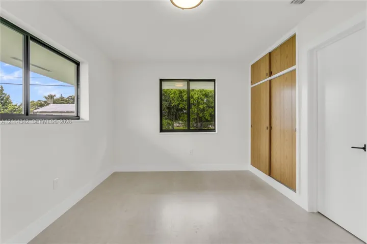 Room featuring large windows with black frames, tile flooring, and integrated wood-finish cabinetry