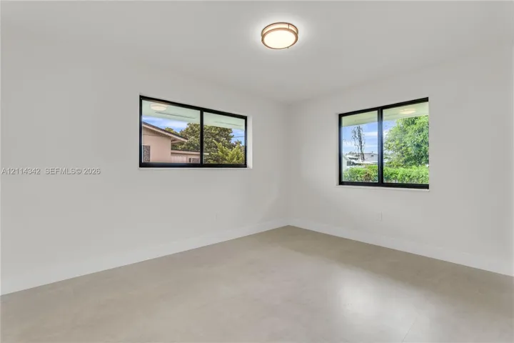 Neutral-toned tile flooring, dual windows with black frames, and a contemporary flush-mount ceiling light fixture