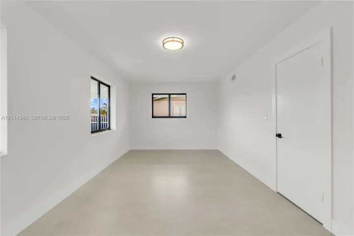 Interior room featuring neutral wall finishes, large-format tile flooring, black-framed windows, and a flush-mount circular ceiling fixture