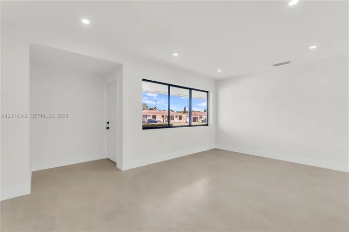Neutral interior featuring expansive windows with black frames, recessed lighting, and large-format tile flooring