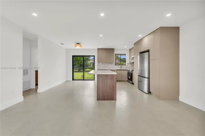 Kitchen featuring a central island, flat-panel cabinetry, stainless steel refrigerator, recessed lighting, and sliding glass doors