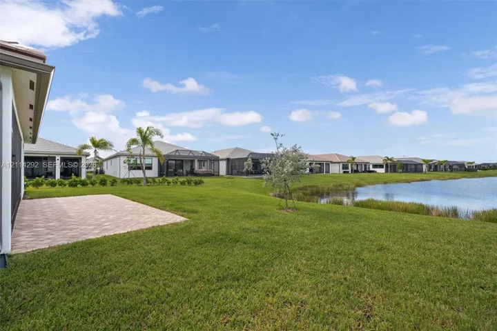 Expansive backyard featuring a paved patio, manicured lawn, and direct water frontage