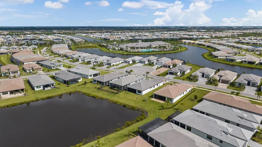 Aerial perspective of a planned community featuring multi-phase housing, extensive waterways, paved street networks, and manicured green spaces
