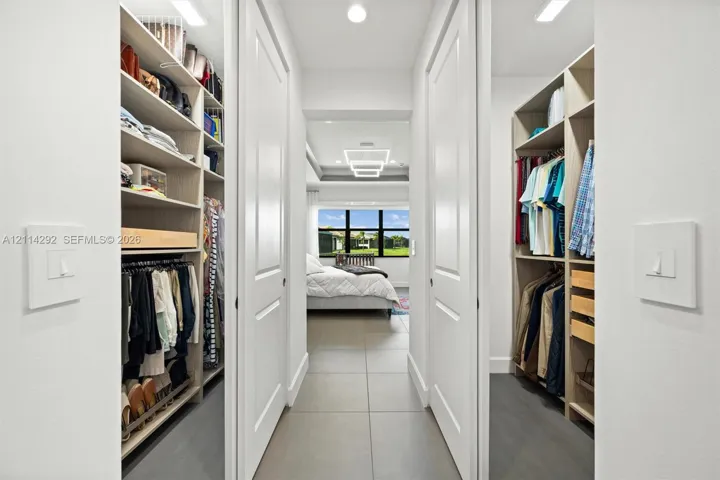 Walk-in closet featuring floor-to-ceiling built-in shelving, hanging rods, pull-out storage drawers, and large-format tile flooring