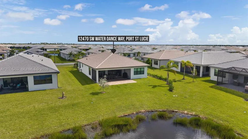 Single-story residence featuring a tile roof, covered rear patio, expansive lawn, and water frontage