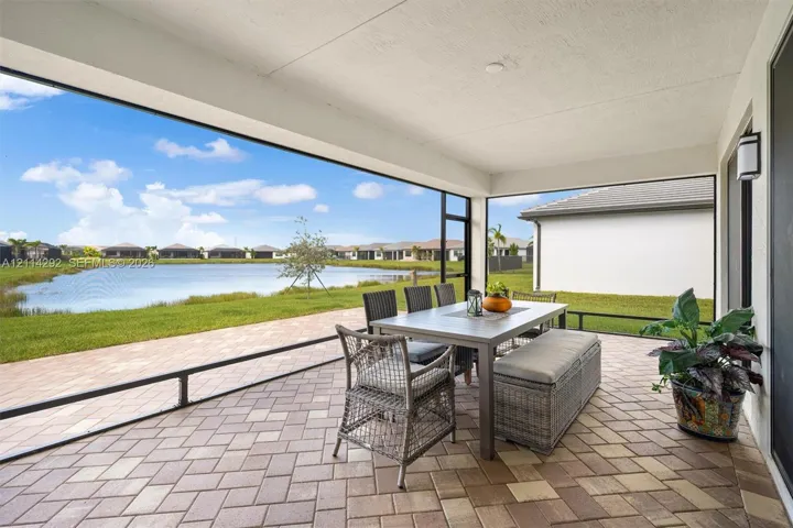 Covered screened-in patio featuring paver flooring and direct water frontage