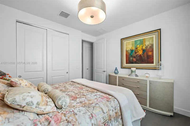 Room featuring dual-panel sliding closet doors, multi-panel interior door, and a drum-style ceiling light fixture