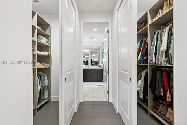 Walk-in closet featuring floor-to-ceiling built-in shelving, multi-level hanging rods, and large-format tile flooring