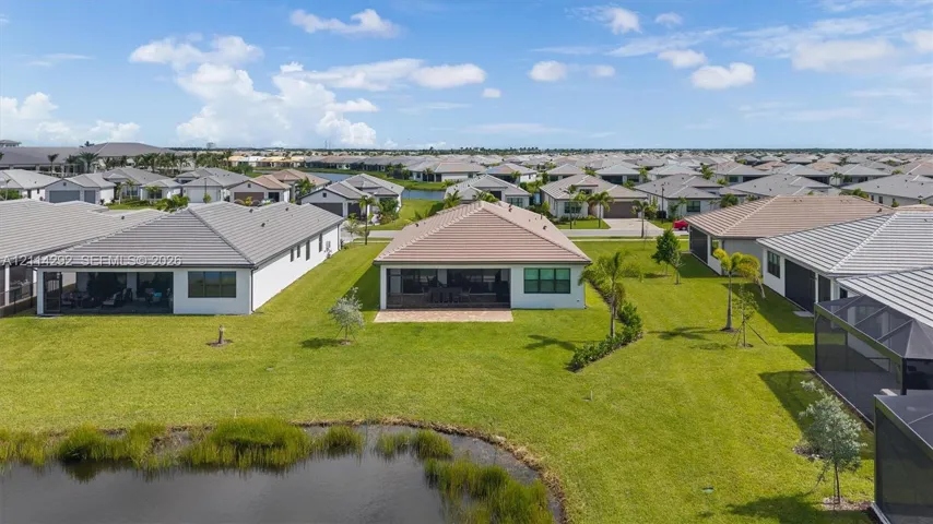 Aerial perspective of a single-story residence featuring a concrete tile roof, paver patio, screened lanai, and waterfront lot