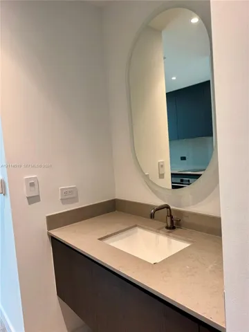 Floating vanity with a stone countertop, undermount sink, dark-finished faucet, and oval wall mirror