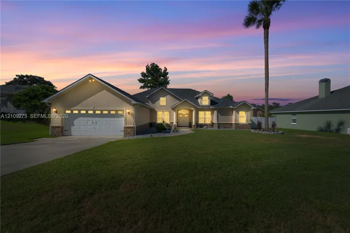 Single-story residence featuring a multi-gable roofline, stone veneer accents, an attached two-car garage, and a concrete driveway