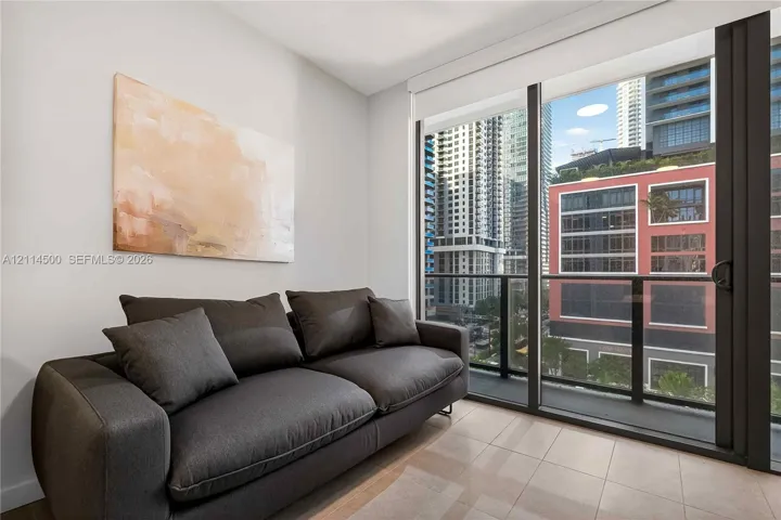 Floor-to-ceiling glass sliding door, neutral tile flooring, and integrated black metal balcony railing