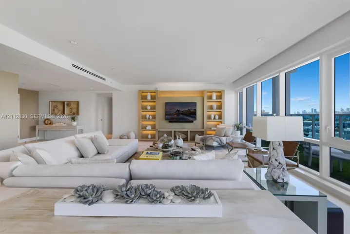Open-concept interior featuring floor-to-ceiling windows, custom built-in cabinetry with integrated shelving, recessed lighting, and smooth-finish walls