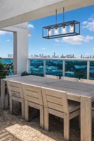 Covered balcony featuring natural stone flooring, a matte black rectangular four-light pendant fixture, and a metal railing