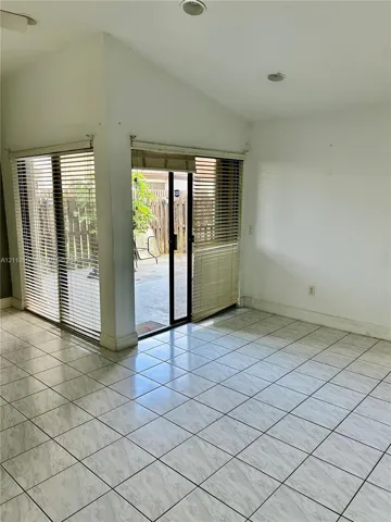 Ceramic tile flooring, vaulted ceiling with recessed lighting, and corner sliding glass doors
