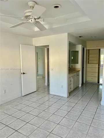 Tiled flooring, ceiling fan, vanity with cabinetry, and built-in shelving unit