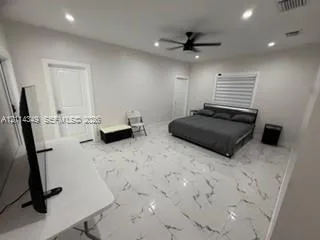 Spacious room featuring light-toned large-format tile flooring with veining, recessed lighting, a modern ceiling fan, and paneled doors