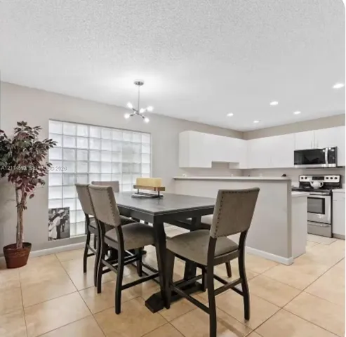 Kitchen featuring white cabinetry, stainless steel appliances, tile flooring, glass block window detailing, and recessed lighting