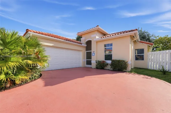Single-story residence featuring a terracotta-tiled roof, stucco exterior, two-car garage, and screened entryway