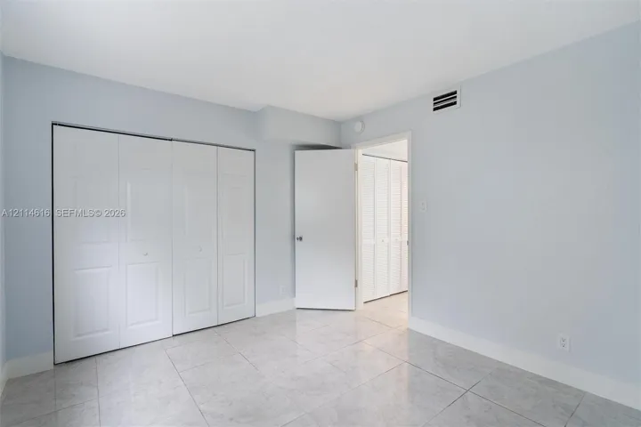 Interior space featuring neutral wall tones, large-format tile flooring, and integrated white bi-fold closet doors