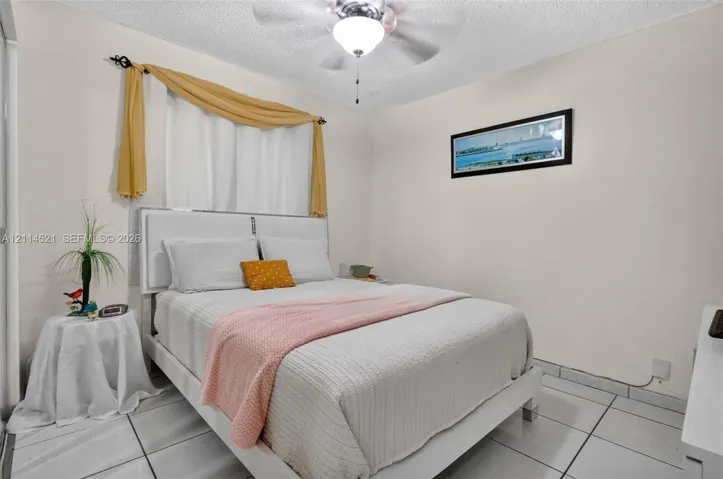 Interior space featuring white tiled flooring, textured ceiling, and a central ceiling fan with integrated lighting