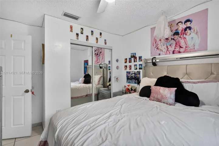 Room featuring white walls, dual mirrored sliding closet doors, a ceiling fan, and six-panel interior door