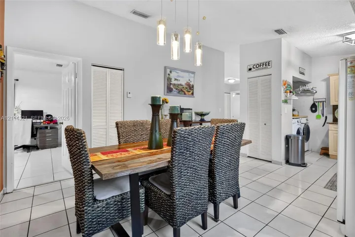 Ceramic tile flooring throughout the open-concept space, modern four-light pendant chandelier, and dual sets of louvered bifold closet doors