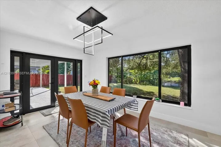 Modern matte black geometric chandelier, large-format tile flooring, and expansive windows with black frames