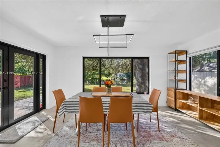 Contemporary geometric chandelier, expansive floor-to-ceiling windows with black frames, wood-finish flooring, and built-in wood shelving units
