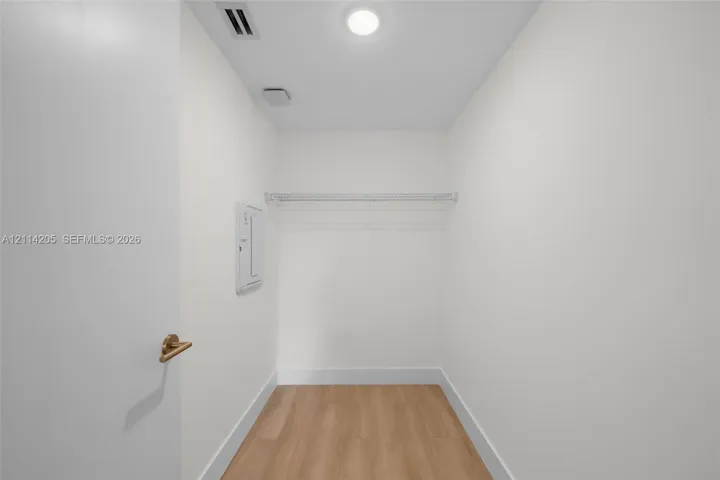 Enclosed storage space featuring wood-finish flooring, a white-coated wire shelf, and recessed ceiling lighting