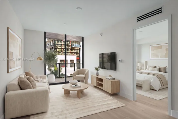 Floor-to-ceiling windows, wood-finish flooring, and a private balcony