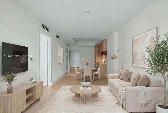 Open-concept interior featuring light wood-finish flooring, recessed lighting, and a modern kitchen with flat-panel cabinetry - staged