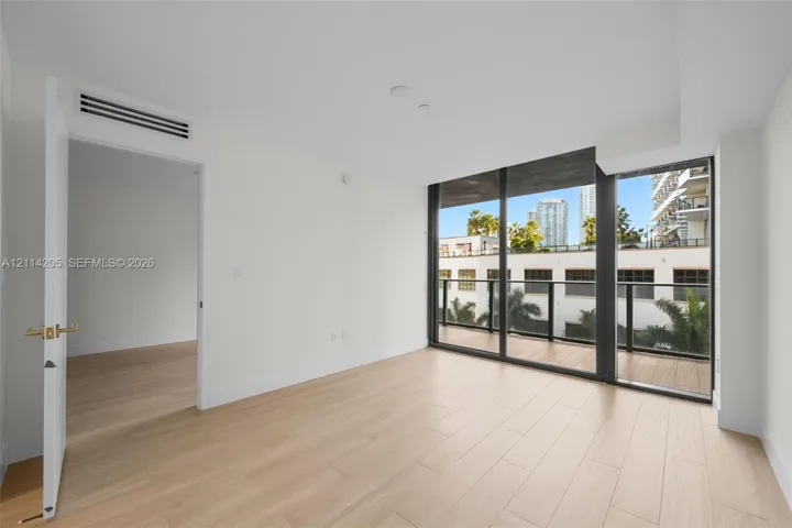 Interior space featuring wood-finish flooring, floor-to-ceiling windows, and a private balcony with a dark metal railing